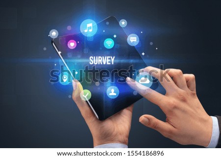 Businessman holding a foldable smartphone with SURVEY inscription, social media concept