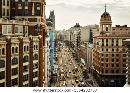 Business shopping area on Gran Via with historical buildings and traffic in Madrid, Spain. Royalty-Free Stock Photo #1554232739
