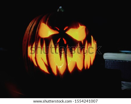 An eerily carved pumpkin, in a dark setting, perfect for Halloween.