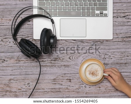 Hand with a Cup of coffee, a laptop and headphones on a wooden table. Job. Freelance.