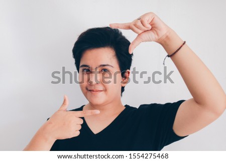 Asian beautiful smiling girl with short hair and showing frame shape by her both hands on the isolated white background. Indonesian Women