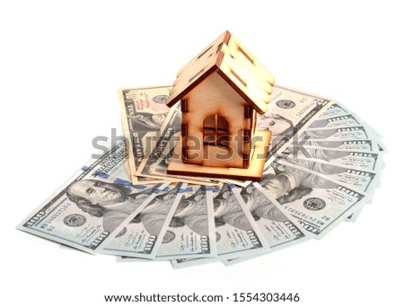 a wooden house and a bunch of American paper notes dollars as a symbol of wealth