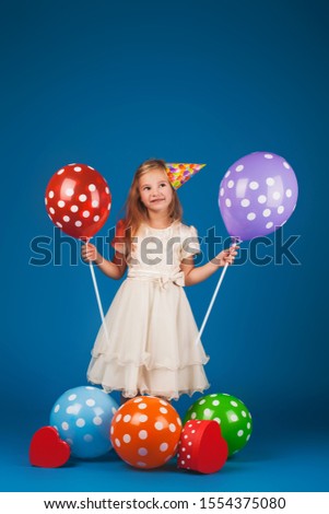 girl with gifts and balloons on the blue background. Studio portrait photos