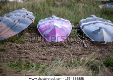 Colourful kayaks pink and mottled colour sitting in grass marsh land