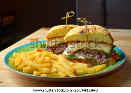 Fast food hamburger and french fries on a wooden plate