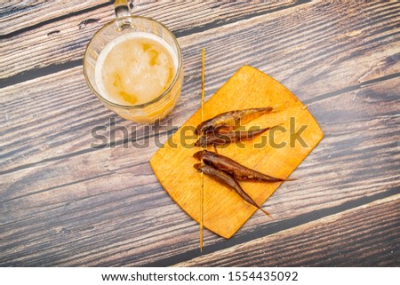 Dried mullet on a wooden Board with a mug of beer on the table. Fish and seafood cuisine. Tasty snack.