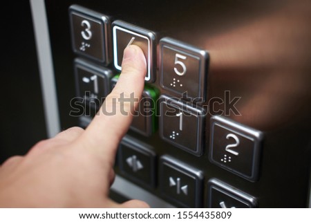 Hand of man pushing braille alphabet elevator button