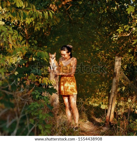 Fairy portrait of young girl and her little dog in the forest. Colorful picture of friendship. Chihuahua dog, place for text.