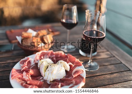 Classic italian antipasti with red wine and sea in background Royalty-Free Stock Photo #1554446846
