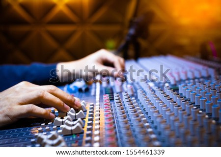 music producer, sound engineer hands working on audio mixing console in recording broadcasting studio. music production, post production, broadcasting concept