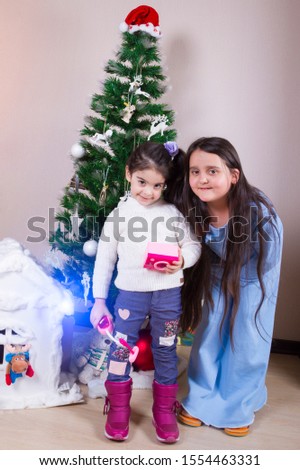 Children girls take pictures at the Christmas tree at Christmas