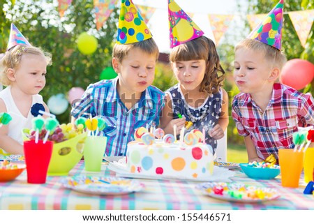 Kids celebrating birthday party and blowing candles on cake