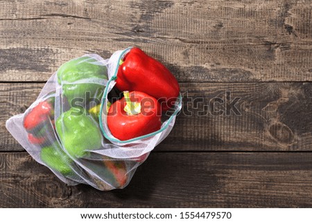 Fresh bell peppers in reusable eco-friendly pouch on wooden background with copy space. eco concept