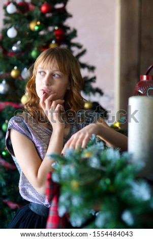 a girl dressed in a holiday dress sitting in a room with Christmas decoration