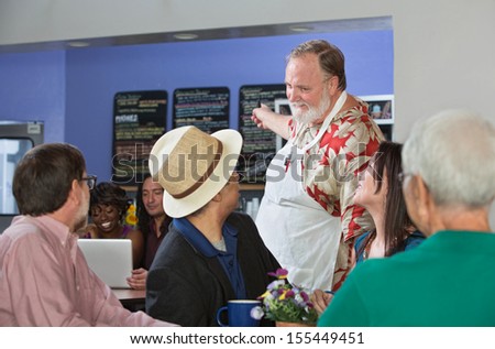 Friendly cafe owner helping customer with menu