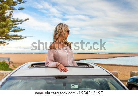 Rolad trip summer beach vibes.  Woman stand in the sunroof of her car by the beach.
 travel, transport, vacation, road trip, carefree 