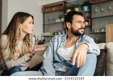 Young woman asking her boyfriend for forgiveness at home Royalty-Free Stock Photo #1554532169