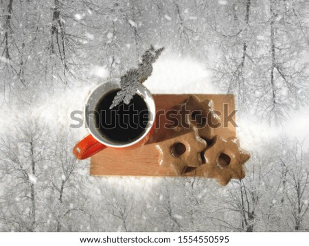Snowfall in winter forest and mug with with black coffee and chocolate cookies. Top view. Flight over snowy winter forest