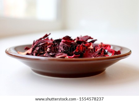 Hibiscus tea. Dried Hibiscus flowers on a brown plate on a white background.