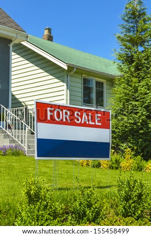 Real Estate Sign "For Sale" on front yard of a house.