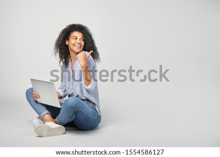 Portrait of a beautiful african woman with laptop on grey background Royalty-Free Stock Photo #1554586127