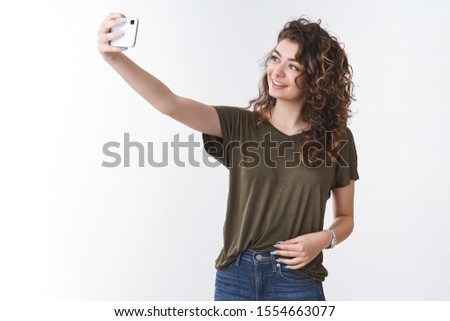 Attractive confident easy-going female blogger taking selfie wanna post new picture personal blog extend arm holding smartphone posing near cool background smiling phone display