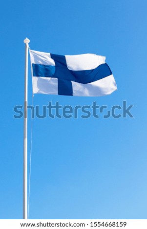 Finnish flag on flagpole. Isolated on blue sky background.