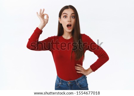 Girl surprised with impressive good outcome, showing okay, ok excellent gesture with widen eyes and opened mouth from amazement, rate somethign awesome and stunning, white background
