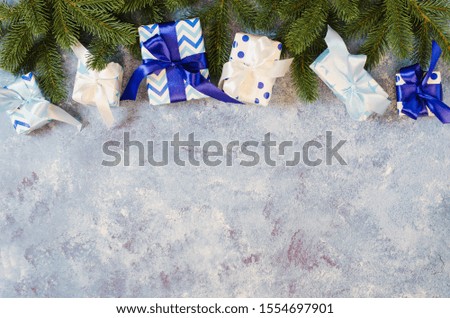 Christmas background. Gift boxes and fir branches with decoration in blue color.