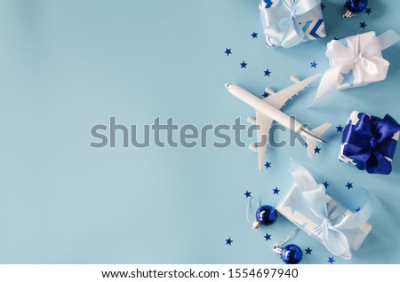 Christmas or New Year travel concept. Toy airplane with passports and gift boxes on blue background. Royalty-Free Stock Photo #1554697940