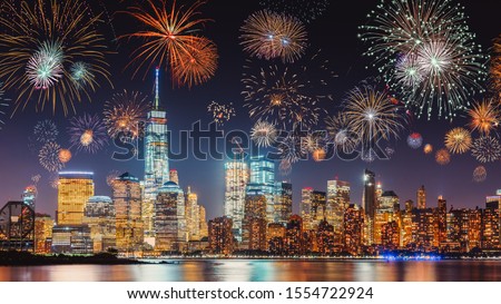 New Years Eve with colorful Fireworks over New York City skyline long exposure with dark blue-purple sky, orange city light glow and reflections in the river Royalty-Free Stock Photo #1554722924