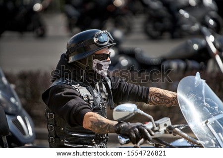 Brutal biker with skeleton mask. unidentified motorcycle rider in a mask takes part in a motorcycle parade           Royalty-Free Stock Photo #1554726821