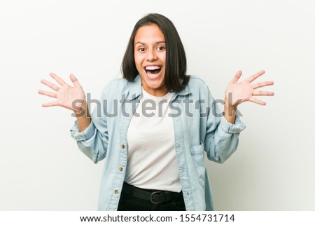 Young hispanic woman celebrating a victory or success, he is surprised and shocked.