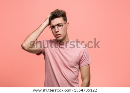 Young cool caucasian man tired and very sleepy keeping hand on his head.