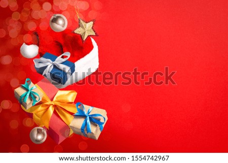 Flying Santa Claus hat, gift box and Christmas decorations on a red background. Holiday concept, christmas. Levitation. Items in the air. Flat lay, top view