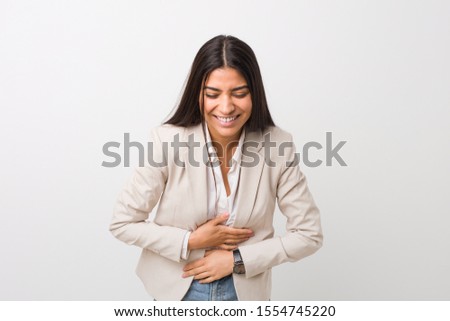 Young business arab woman isolated against a white background laughs happily and has fun keeping hands on stomach.