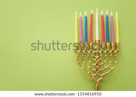 Religion image of jewish holiday Hanukkah with menorah (traditional candelabra) and candles over pastel green background. top view, flat lay