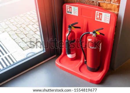 Two red tank of fire extinguisher water and CO2 (Carbon Dioxide) service on the floor in office, school or shopping mall. Indoor red fire extinguisher for safety.