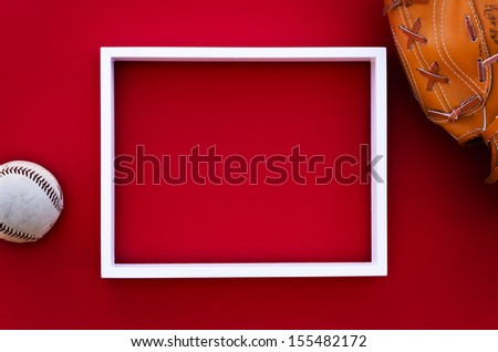 empty picture frame on a red wall with worn baseball glove and ball