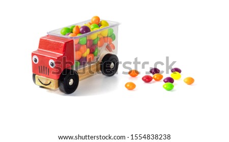 multi-colored candies fell from the back of a red children's toy car. Candy boom. White background