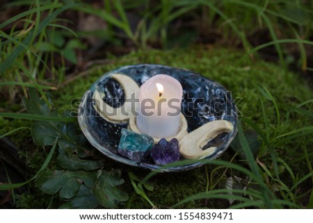 A small vax candle in the black ceramic candle-holder on the moss
