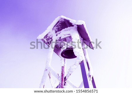 Surreal big iron bell covered in snow against a purple neon sky