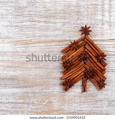 Christmas card with fir tree made from spices cinnamon sticks, anise star on rustic wooden background. Celebration concept. Place for text, Flat lay, top view, copy space