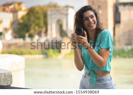 Smiling girl in an Italian city with a camera in her hand.
