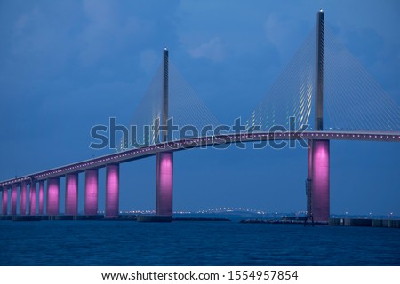 Closeup of the iconic Sunshine Skyway Bridge spanning the wide mouth of beautiful Tampa Bay in central Florida lit up in pink LED lights to commemorate Breast Cancer Awareness Month.