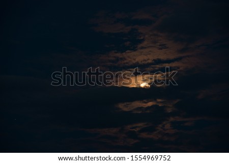 Beautiful full moon in the night cloudy sky.