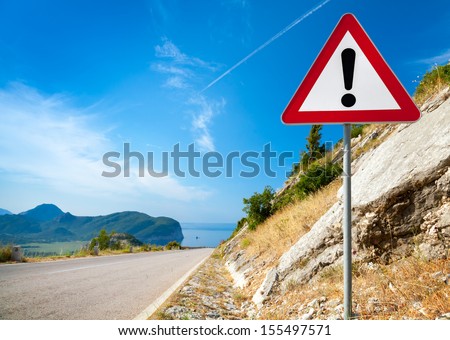 Warning road sign with an exclamation mark in red triangle on mountain highway Royalty-Free Stock Photo #155497571