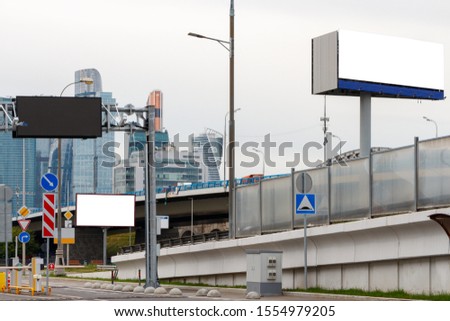 Two horizontal billboards on the background of skyscrapers and a bridge.