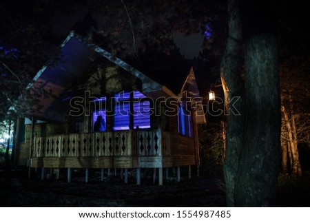 Old house with a Ghost in the forest at night. Horror silhouette at the window. Old building in forest. Surreal lights. Horror Halloween concept
