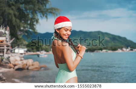Christmas beach vacation - cute mixed race Asian  girl portrait in Santa hat  relaxing posing  a tropical destination during winter holidays.
